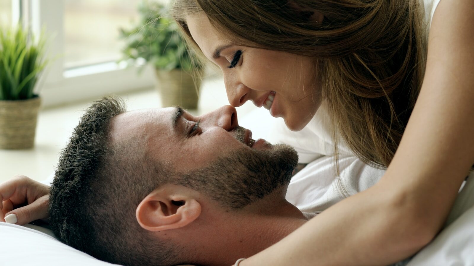 Couple lying in bed, noses touching