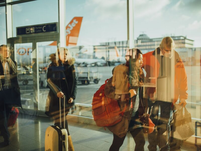 Passengers moving through an airport gate area with visible airplanes outside.